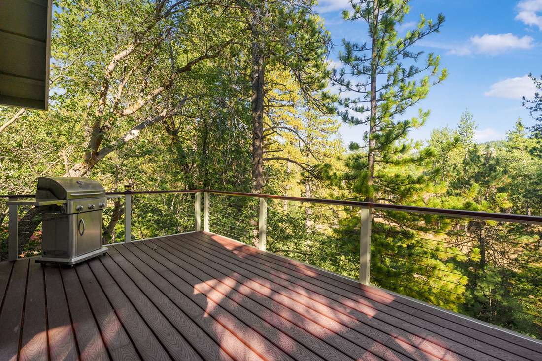 Wooden deck looking out into tall pines.