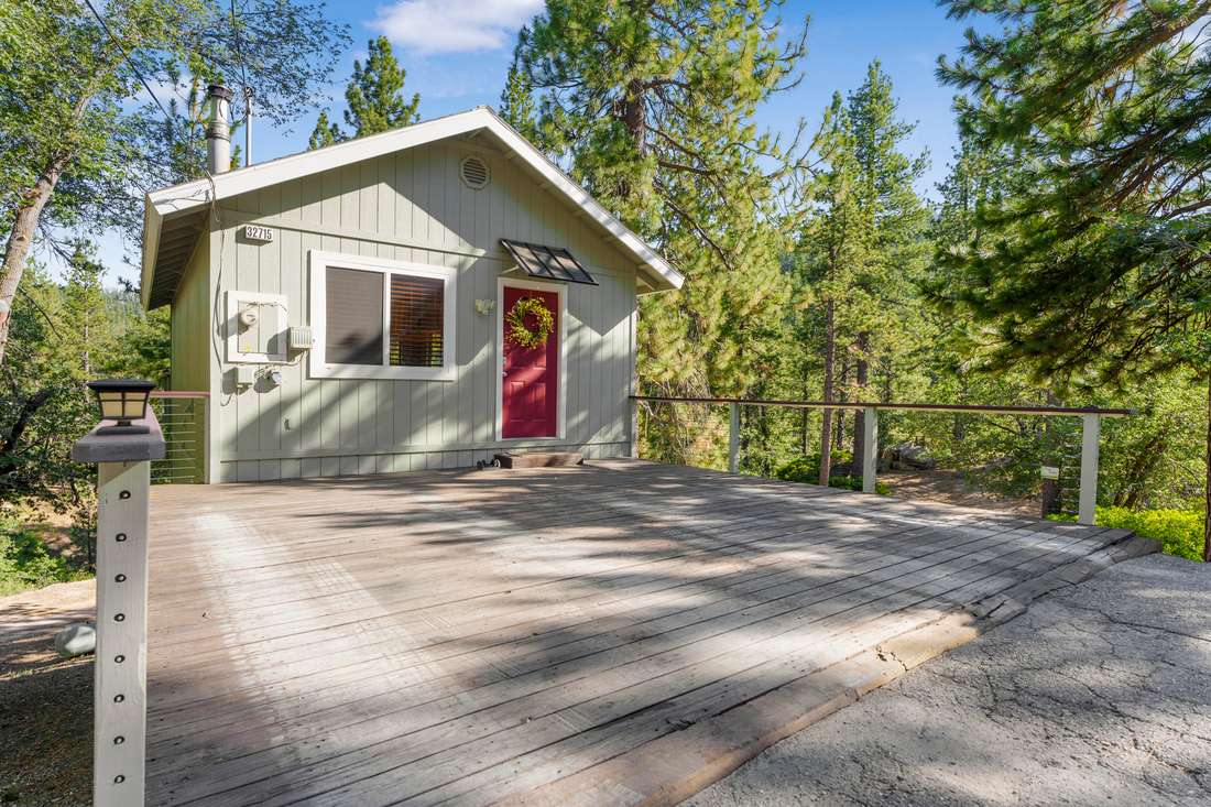 Exterior of a mountain cabin with a red door among the trees.