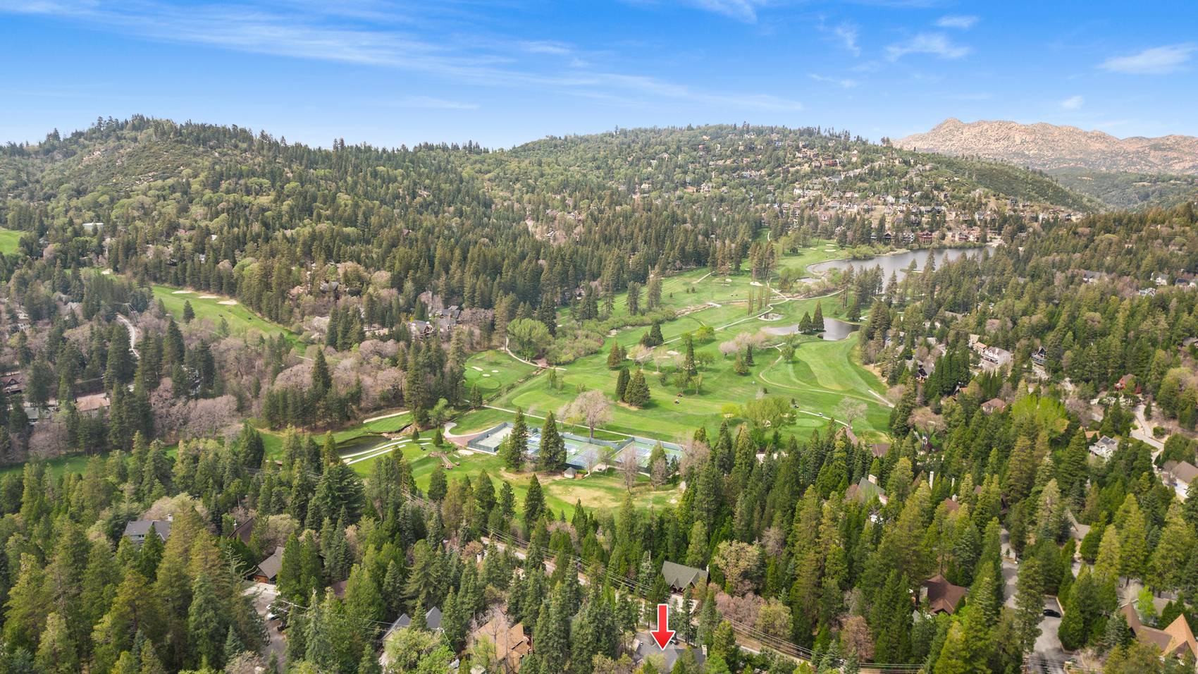 Aerial over an open meadow with forested ridgelines behind.