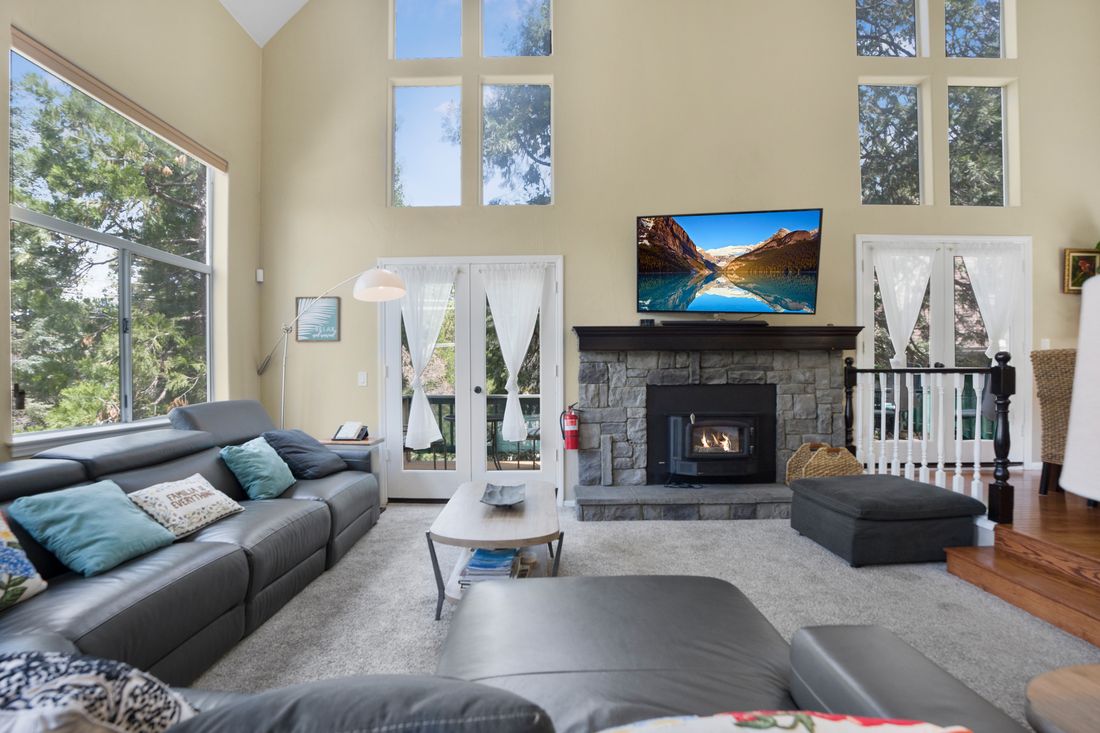 Great room with a stone fireplace and a vaulted ceiling.