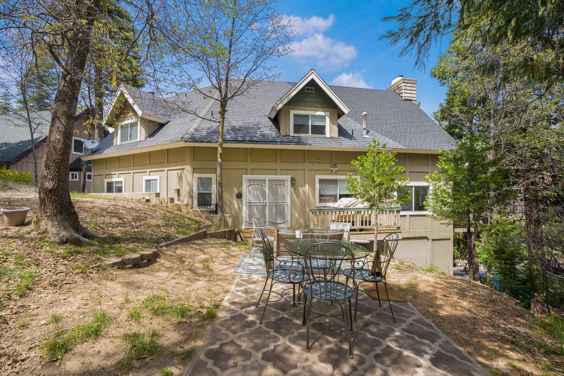 Rear elevation of the home with a deck under tall trees.